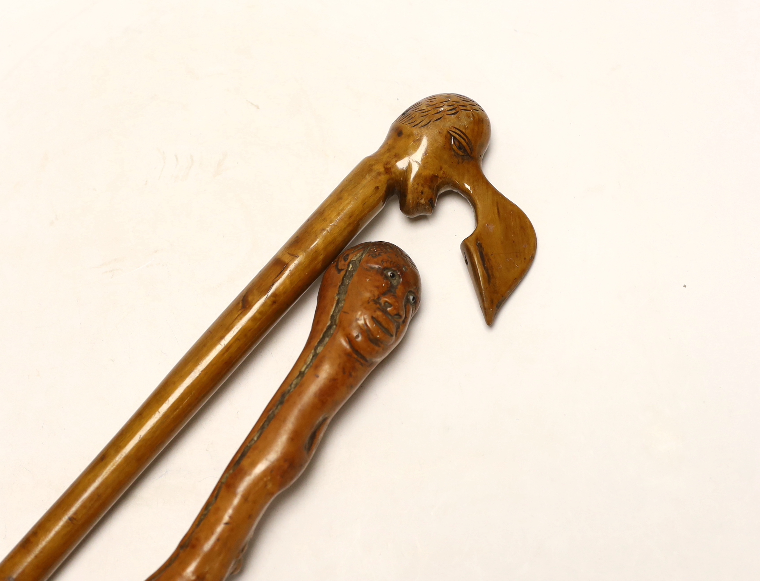 Two walking canes including a Greek olive wood example with carved head handle, largest 89cm in length